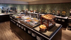 Montaje de bufé con diferentes alimentos y estaciones de cocina.