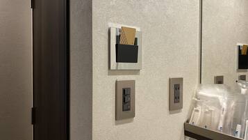 A bathroom with a textured wall, a mirror, a towel rack, and a shelf with toiletries.