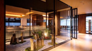 Un interior moderno con separador de vidrio, zona de estar y jardín decorativo de rocas.