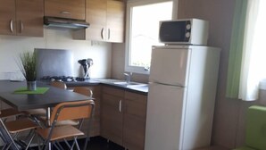 A compact kitchen with a dining area, a refrigerator, a microwave, and a window providing natural light.