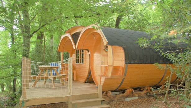 A wooden cabin with a covered porch and a fenced deck area.