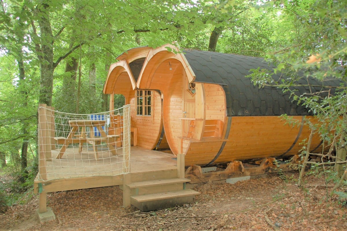 A wooden cabin with a covered porch and a fenced deck area.