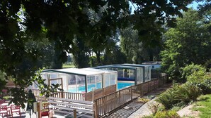 A poolside area with glass enclosures, wooden deck, and outdoor seating.