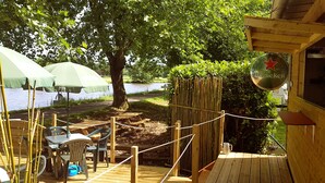 A wooden deck with tables and chairs, a Heineken sign, and a view of a lake.