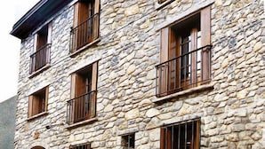 Un bâtiment en pierre doté de nombreuses fenêtres et d’un balcon.