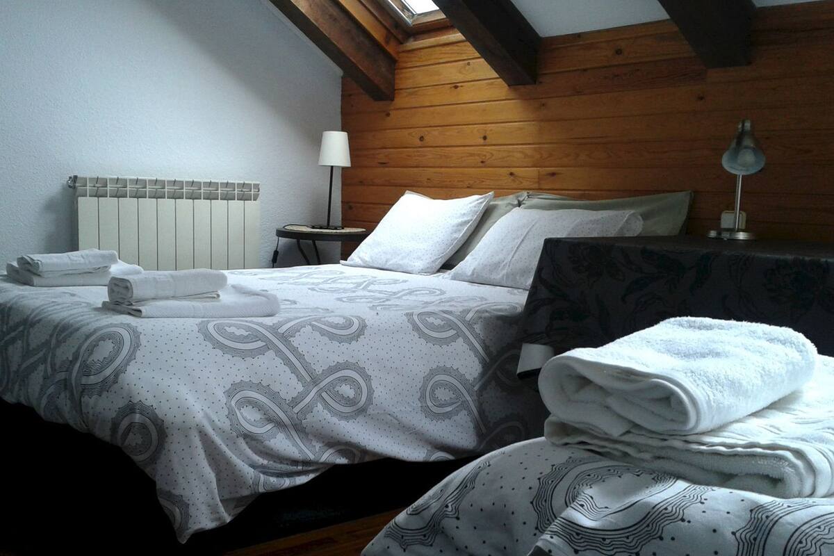 A bedroom with a bed, pillows, a bedside table, and a lamp.