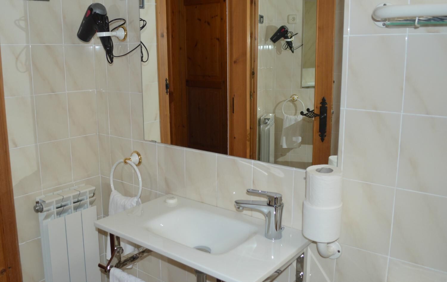 A bathroom with a white sink, a mirror, and two hair dryers mounted on the wall.