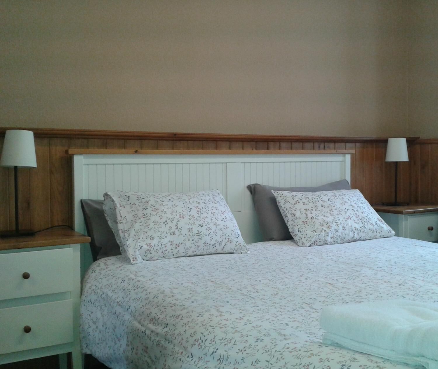 A bedroom with a bed, two bedside tables, and a nightstand.