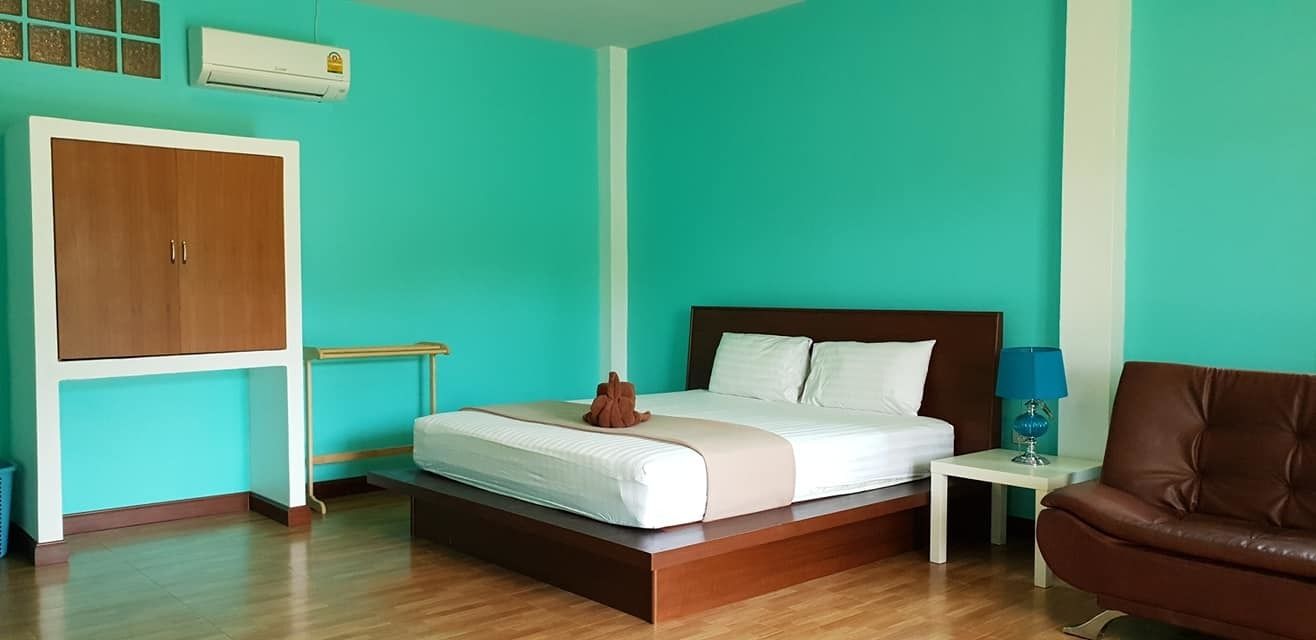 A bedroom with a bed, a brown leather chair, a nightstand, and a wardrobe.