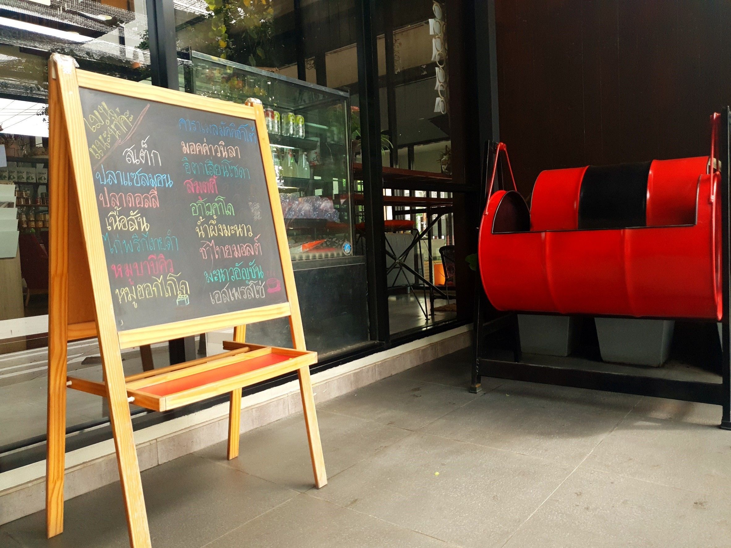 Een schoolbordmenu voor een restaurant, met een rode stoel en een glazen vitrine op de achtergrond.