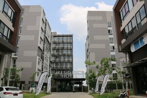 Fachada moderna de un hotel con un letrero destacado, varios pisos y abundante vegetación.