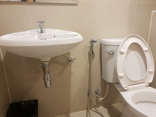 Un baño con lavamanos, inodoro y ducha blancos.
