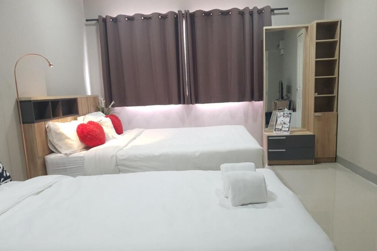 Una habitación de hotel con dos camas, un armario, un espejo y una mesita de noche.