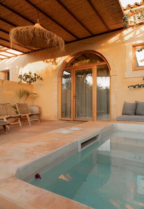 A pool area with a clear pool, lounge chairs, and a ceiling fan. - IUTA Glamping & Farm (Avola)