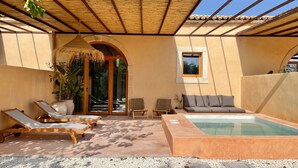 Uma área externa coberta com piscina, espreguiçadeiras e um espaço para sentar.