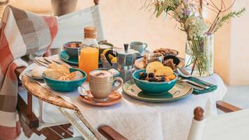 Une table de petit-déjeuner dressée avec des assiettes, des bols et un vase rempli de fleurs.
