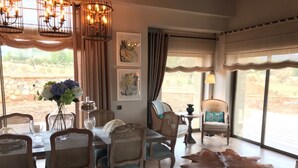 A dining area with wicker chairs, a dining table, and a large leather rug.
