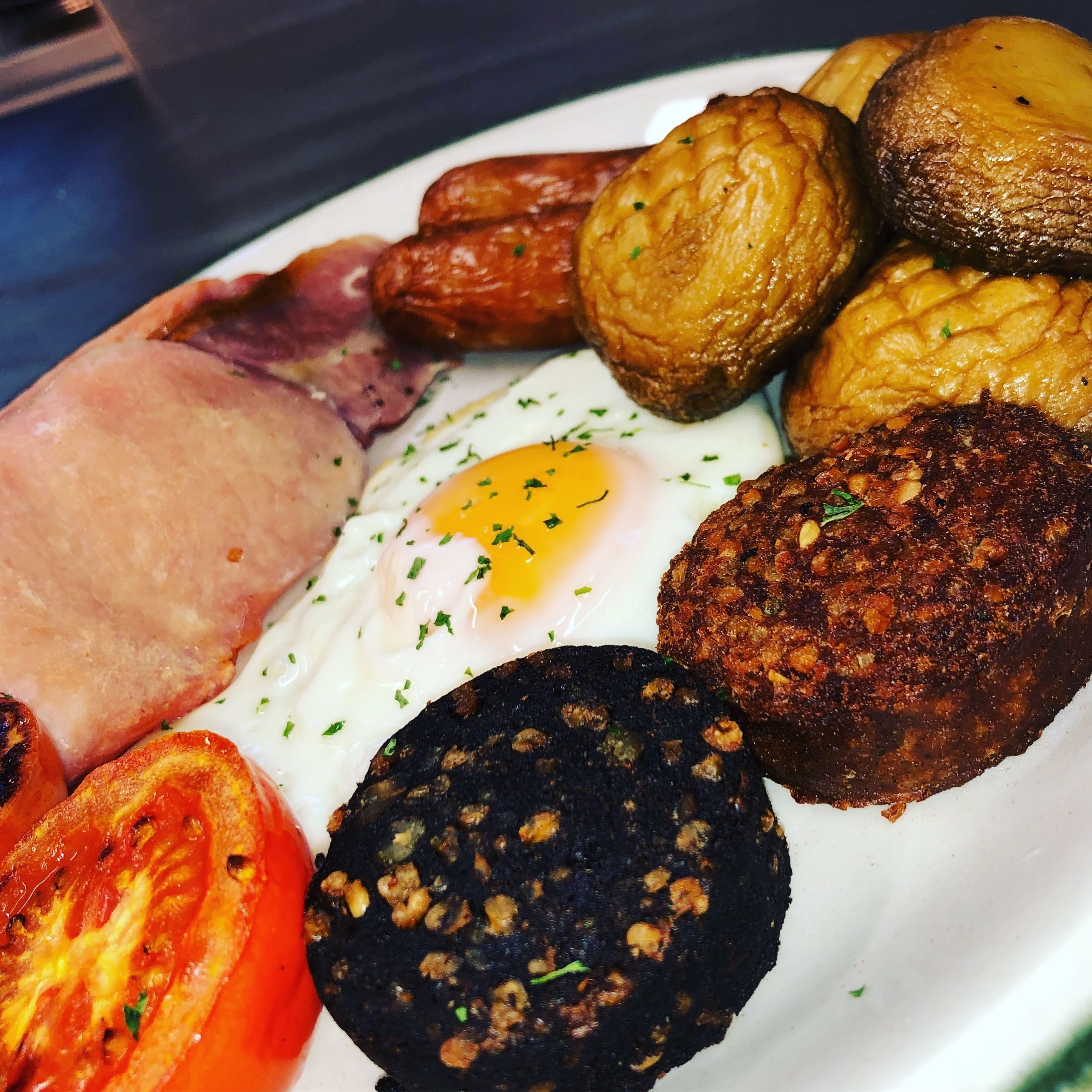 Un plato de comida para el desayuno con huevos, salchichas, tocino y tomates.