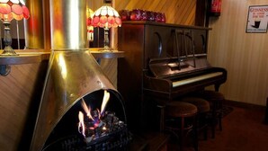 Ein gemütlicher Raum mit Kamin, Klavier und einem Guinness-Schild an der Wand.