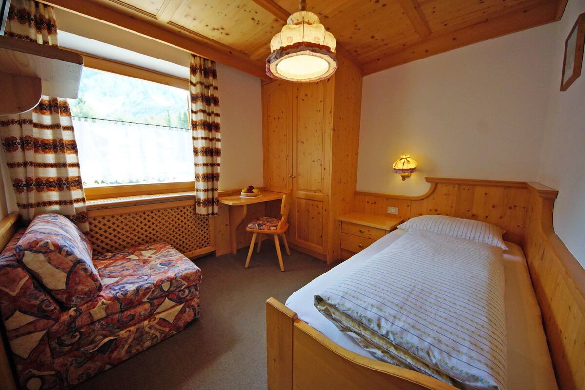 A cozy room with a bed, a desk, and a chair.