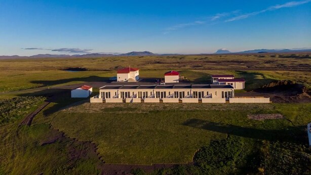 Vista aérea de un conjunto de edificios, rodeado de campos abiertos y montañas distantes.