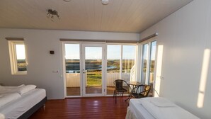 Un dormitorio con dos camas, un balcón con vistas y una pequeña mesa con sillas.