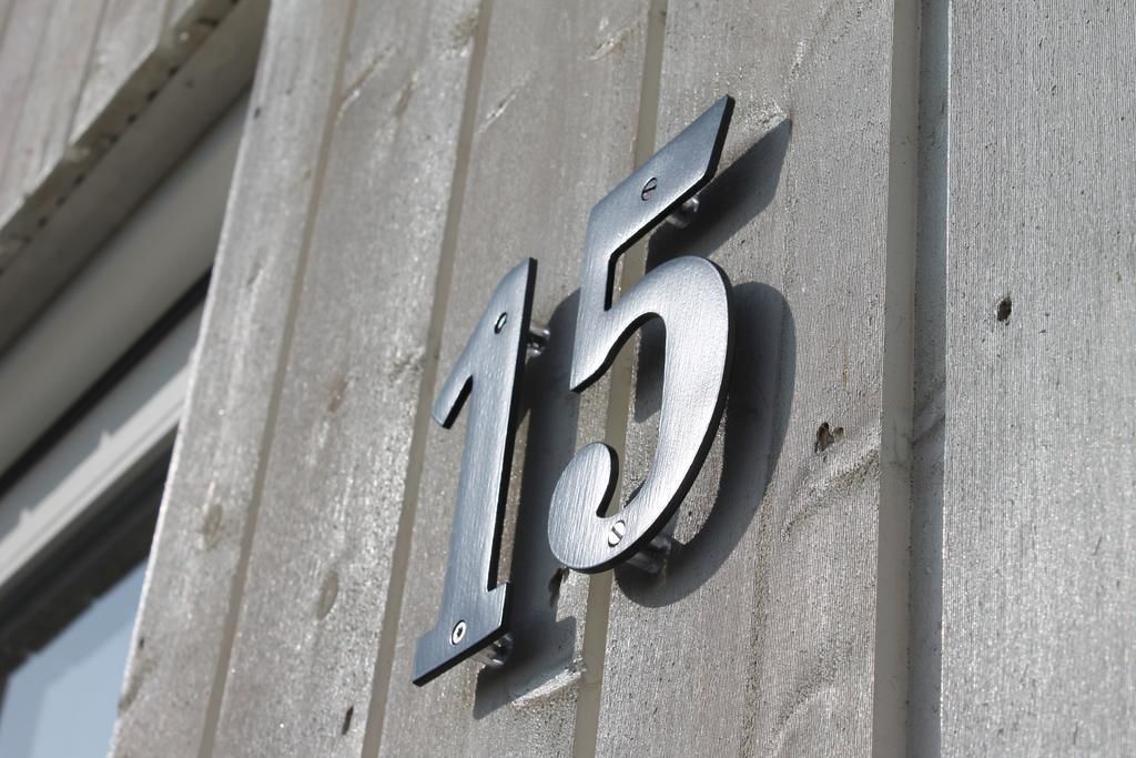 A metal number '15' mounted on a concrete wall.