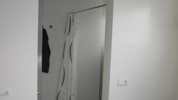 A bedroom with a bed, a green towel, and a door leading to a bathroom with a shower curtain. - Grímstunga Guesthouse (Myvatn)