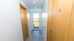 Pasillo con puertas de madera numeradas 6 y 7, que da a una puerta con vista a un campo.