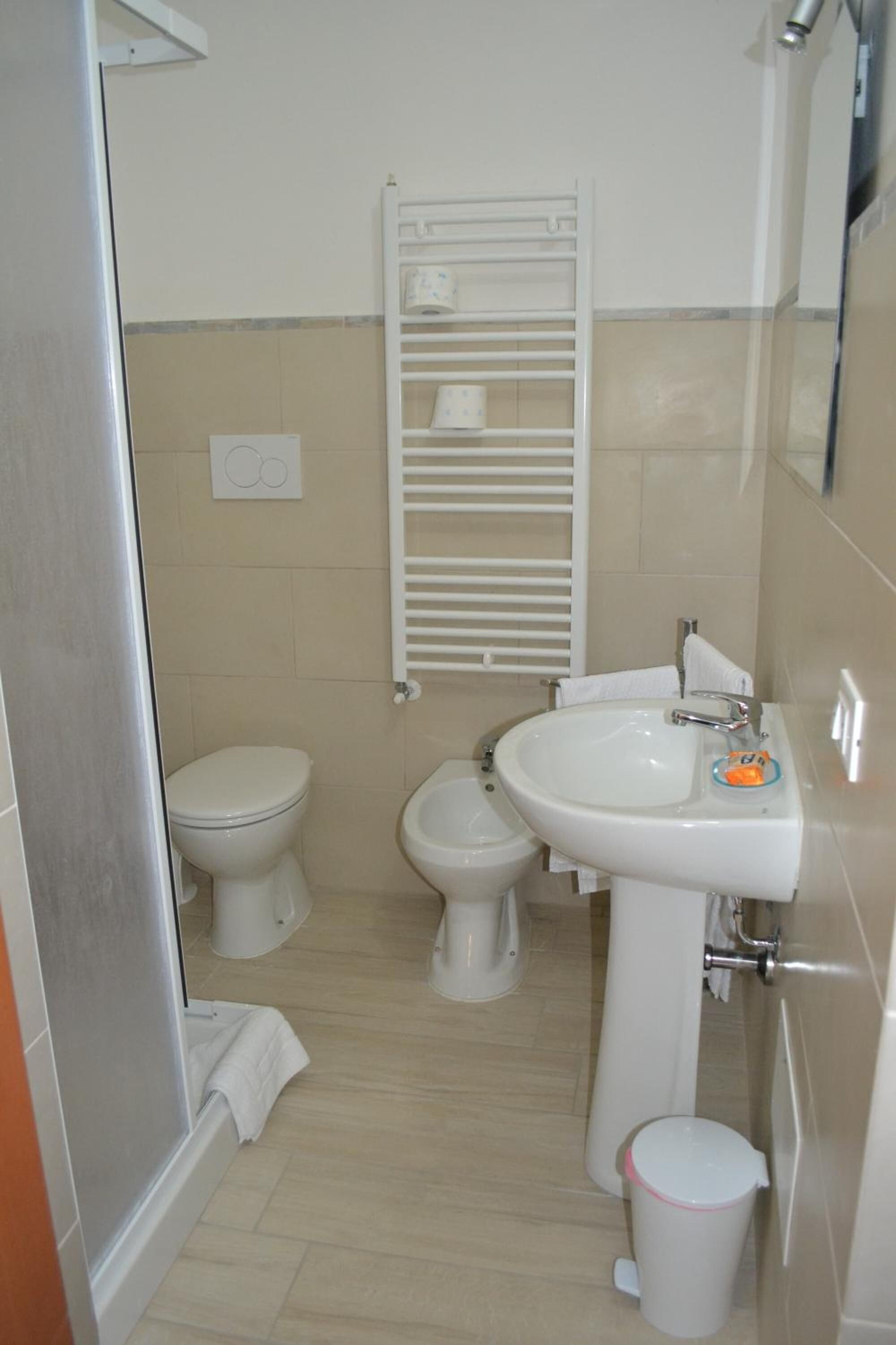 A bathroom with a toilet, bidet, sink, and a towel rack.