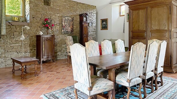 Une salle à manger avec un mur en pierre, une table en bois et des chaises.