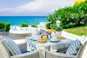 Enjoy a peaceful ocean view breakfast with a table set for two, featuring fresh fruit, pastries, and a steaming teapot.