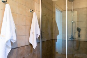 Enjoy a clean and hygienic bathroom with a glass shower enclosure, handheld showerhead, and wall-mounted faucet.