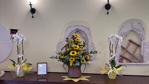 A reception desk with a vase of sunflowers, two wall-mounted lights, and decorative arches. - B&B Sei Stelle (Sulmona)
