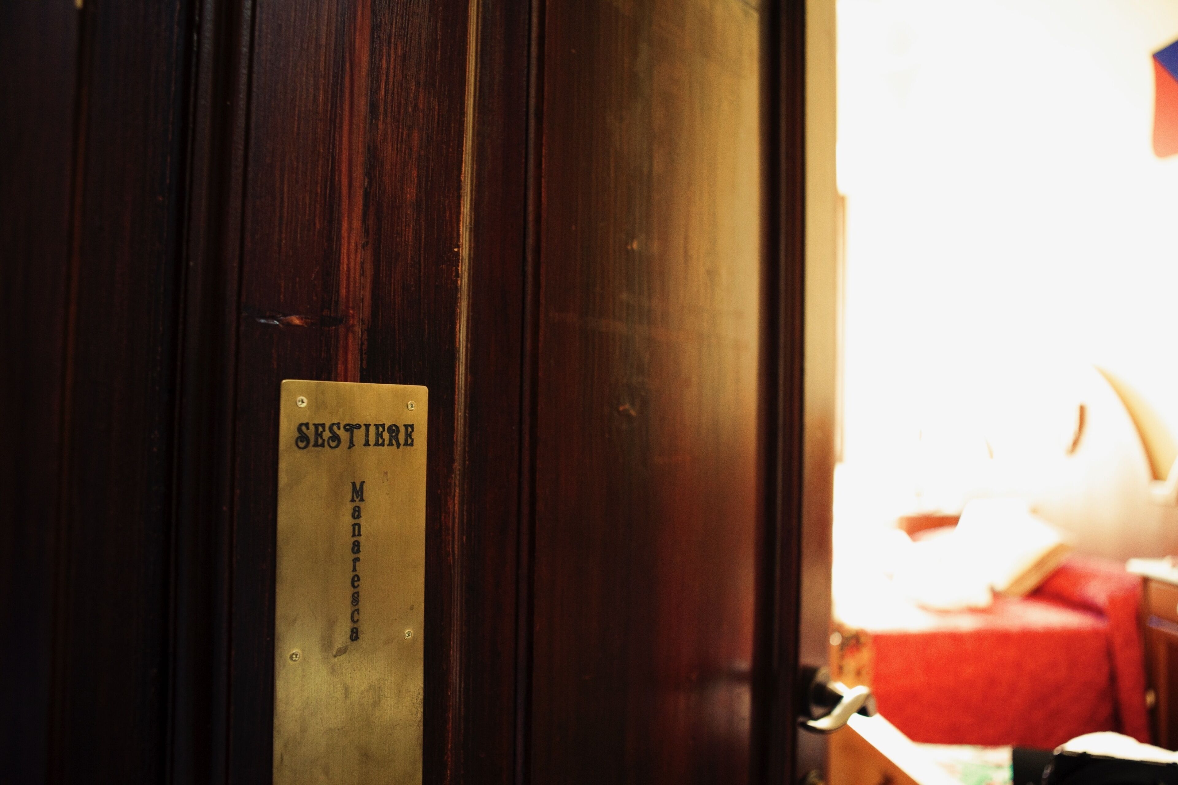 A wooden door with a brass plate that reads "SESTIRE" and "Manares."