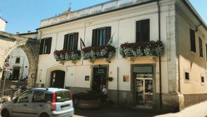 A building with a white facade, two visible shop fronts, and a parked car in front. - B&B Sei Stelle (Sulmona)