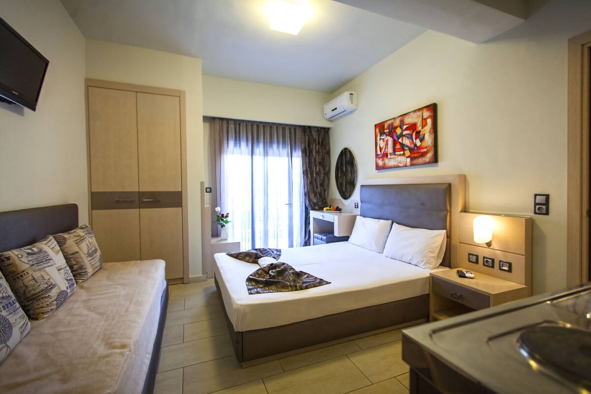 A hotel room with a bed, a sofa, a desk, and a TV.