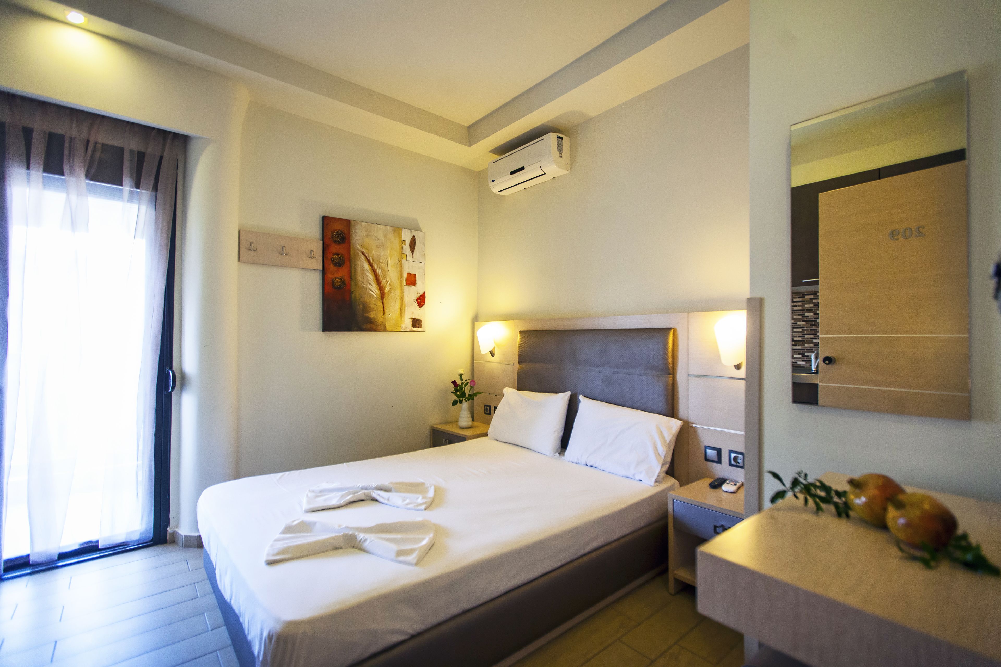Una habitación de hotel con cama, mesita de noche y espejo.