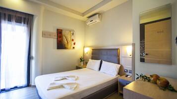 Una habitación de hotel con cama, mesita de noche y espejo.