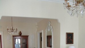 A dining area with a wooden table and chairs, a chandelier, and a mirror on the wall. - La casa di Ida (Locri)