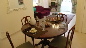 A dining area with a round table set for four, surrounded by wooden chairs. There is a coffee pot, a teapot, and a plate of food on the table. - La casa di Ida (Locri)
