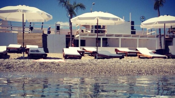A beachside hotel with sun loungers and umbrellas, a pool with clear water, and a building with a balcony. - La casa di Ida (Locri)