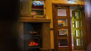 A room with a fireplace, a stained glass window, and a wooden door. - The Old Mill (Durham)