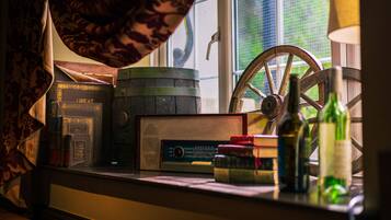 A vintage radio, books, a wooden barrel, and bottles on a window sill.