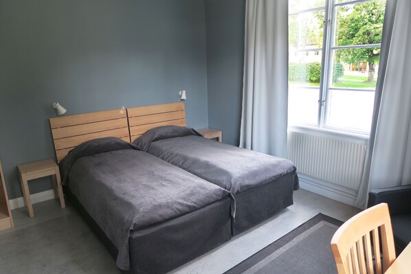 Un dormitorio con una cama doble, una mesita de noche, una silla y una ventana con cortinas.