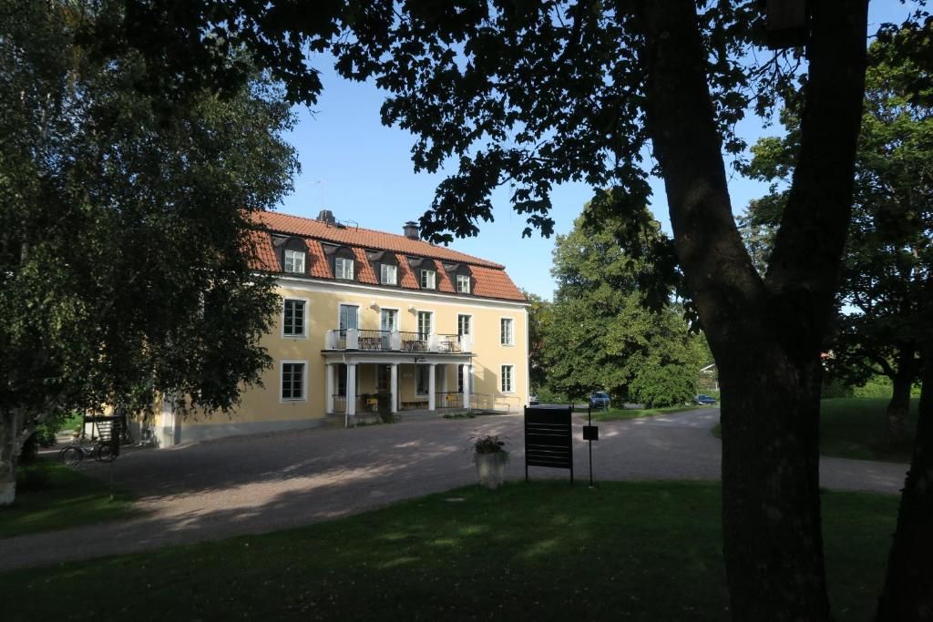 A large, yellow building with a red-tiled roof, a covered porch, and a paved driveway.