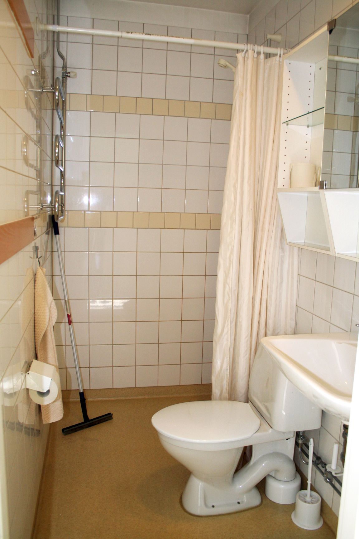 A small, compact bathroom with a toilet, a shower, and a sink.