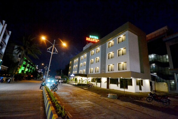 Um hotel com vários andares, uma entrada bem iluminada e uma placa visível.