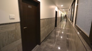 A hallway with a marble floor, a door labeled "102", and a light switch on the wall. - Hotel Dhantara (Rahata)