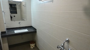A bathroom with a sink, mirror, shower, and toilet. - Hotel Dhantara (Rahata)
